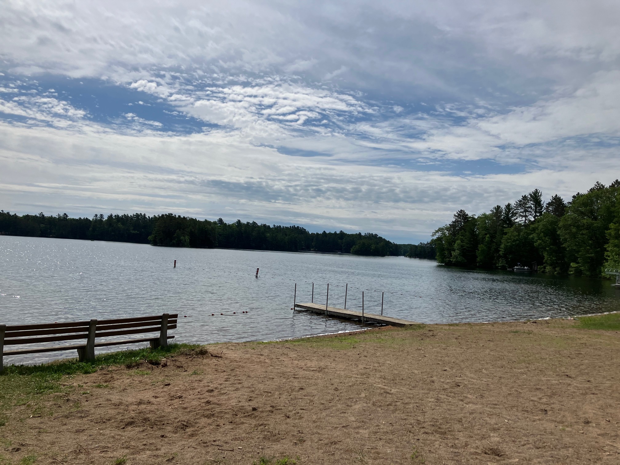 A sandy public beach beside the calm waters of a Northwoods lake